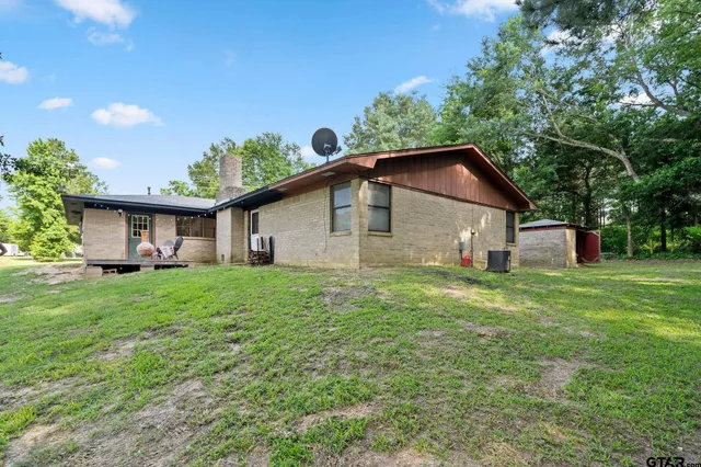 a view of a yard in front of a house with plants and large tree