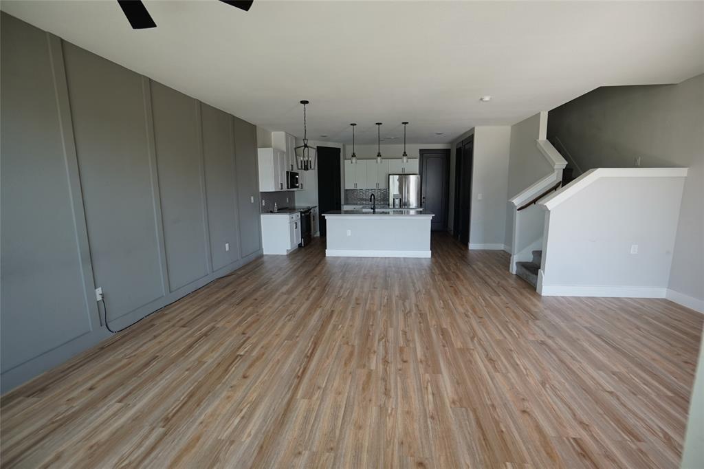 1764 Palladio Loop Princeton, TX 75407 - Photo 4 of 40 Spacious interior featuring wood-finish flooring, a contemporary kitchen with a central island and pendant lighting, and a paneled accent wall