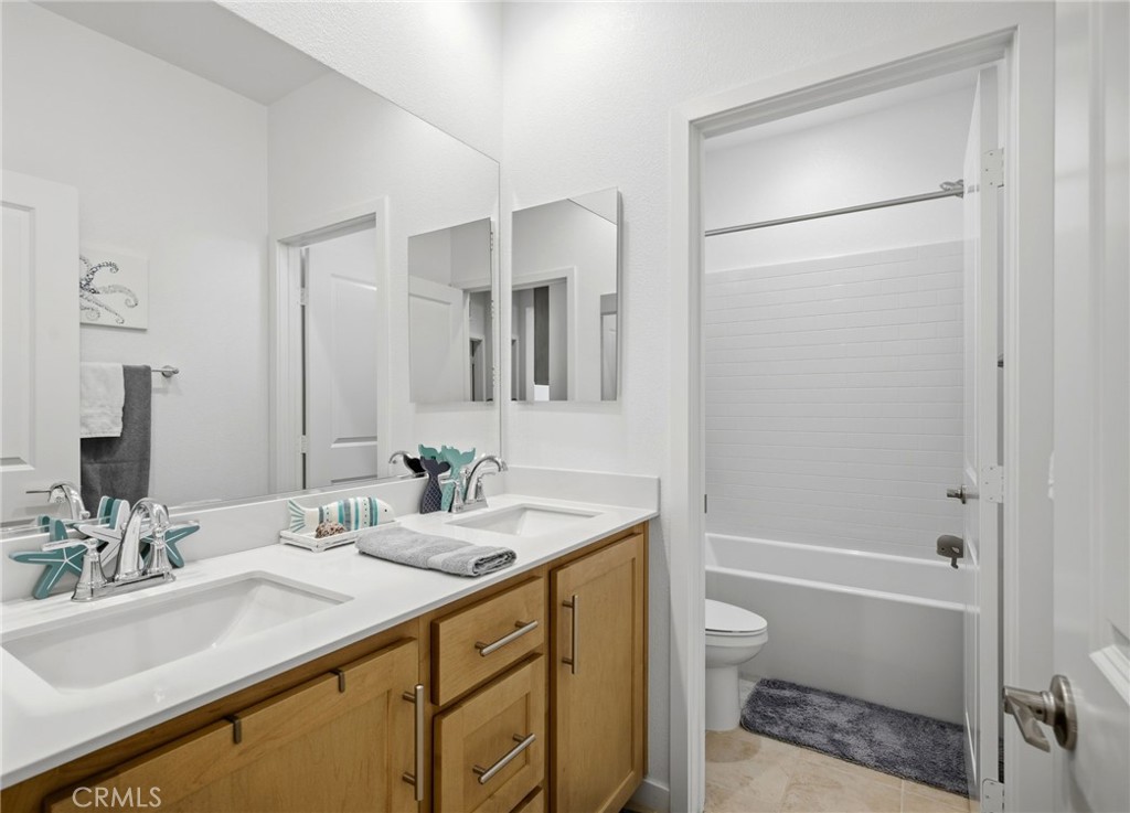 32243 Penstemon Way Temecula, CA 92591 - Photo 17 of 26 a bathroom with a granite countertop sink a toilet and shower