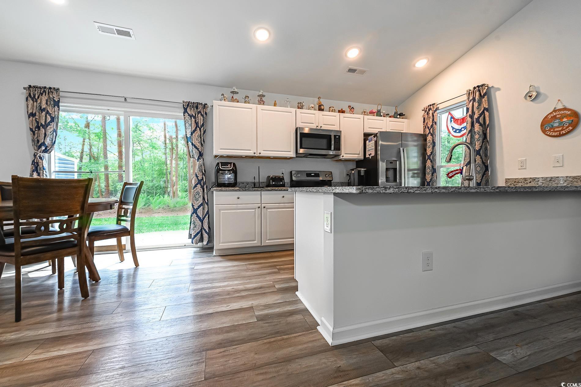 67 Bossie Lane Georgetown, SC 29440 - Photo 6 of 33 Kitchen with appliances with stainless steel finishes, dark stone counters, white cabinets, a peninsula, and dark wood finished floors