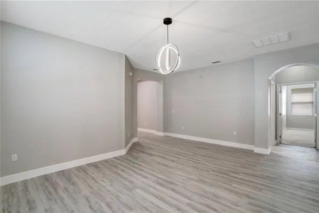 a view of an empty room with window and wooden floor