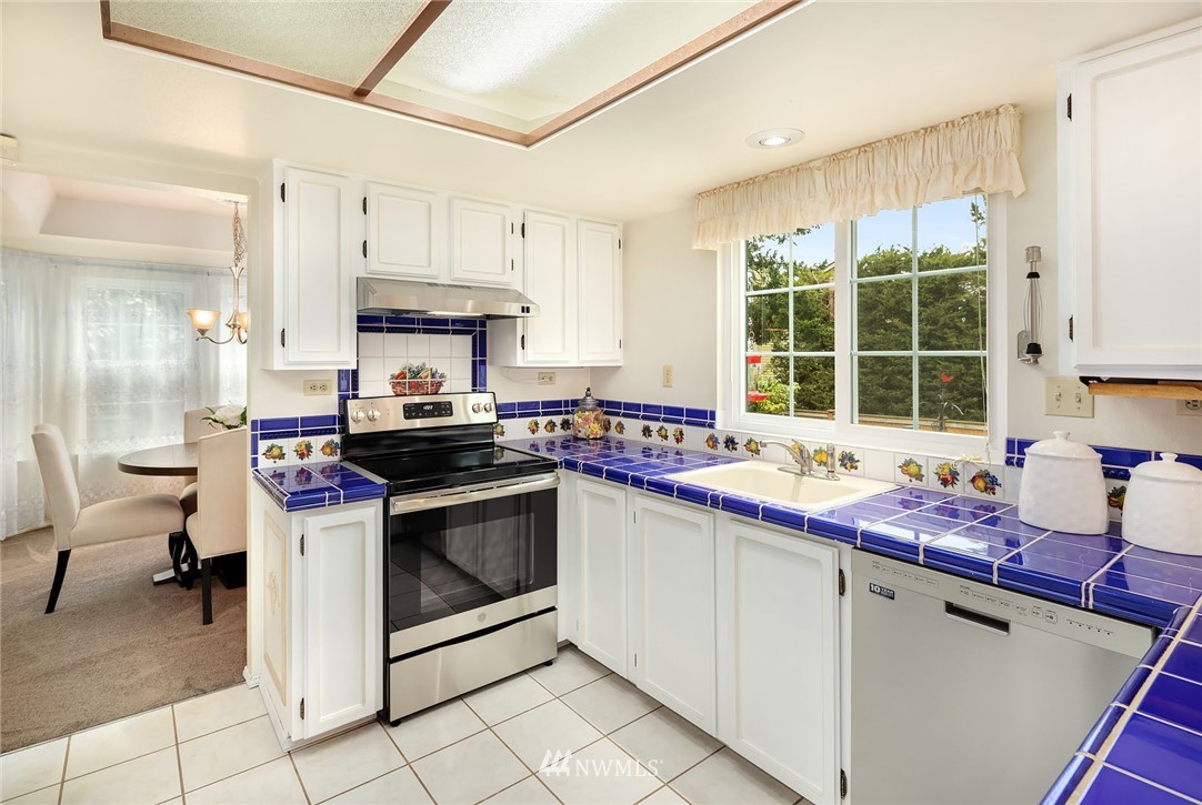 210 237th Place Southwest Bothell, WA 98021 - Photo 6 of 23 a kitchen with stainless steel appliances a stove a sink and white cabinets