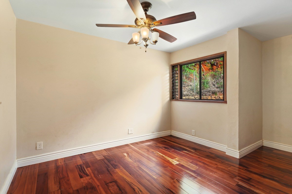 4701 Kawaihau Road, Unit L102 Kapaa, HI 96746 - Photo 15 of 22 an empty room with wooden floor chandelier fan and windows