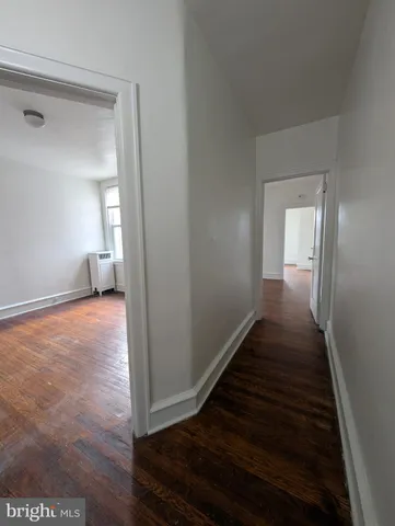a view of a hallway to an empty room and wooden floor
