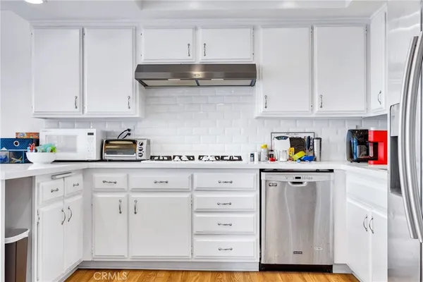 a kitchen with white cabinets and appliances