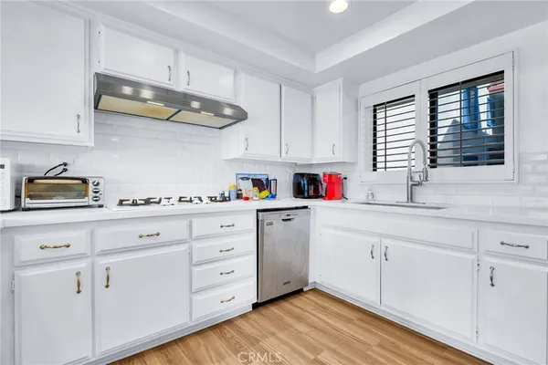 a kitchen with white cabinets and window