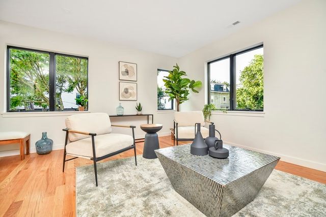 a living room with furniture large window and wooden floor
