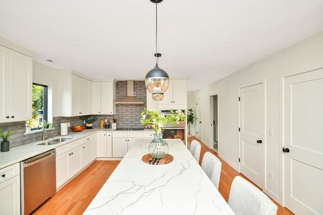 a large white kitchen with a window and stainless steel appliances