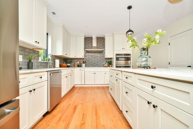 a large kitchen with granite countertop a sink white cabinets and stainless steel appliances
