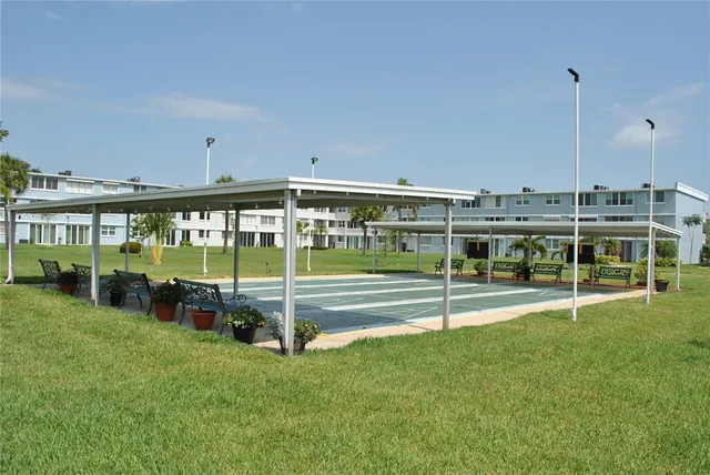 a view of a swimming pool with lawn chairs and large trees
