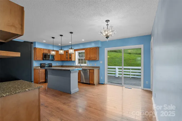 a open kitchen with granite countertop a stove top oven a sink and dishwasher with wooden floor