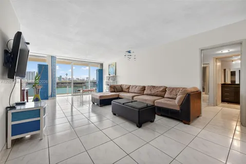 a living room with couches a flat screen tv and a kitchen view
