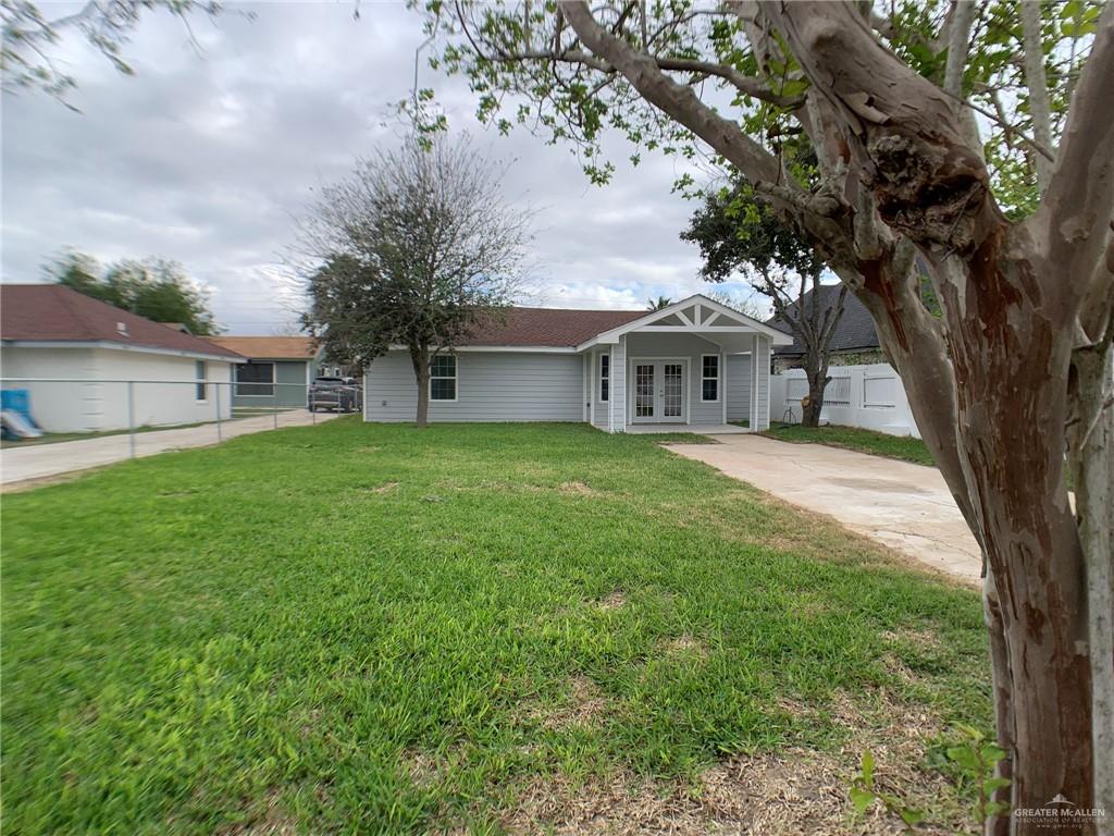 10824 Compadres Street Mercedes, TX 78570 - Photo 3 of 19 a front view of a house with a garden and trees