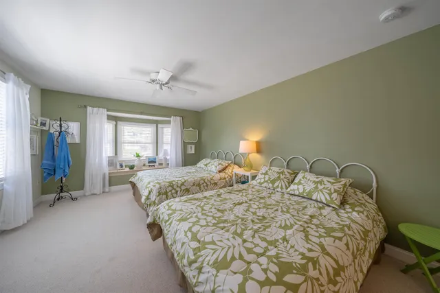 a bed sitting in a spacious bedroom next to a window and a chandelier