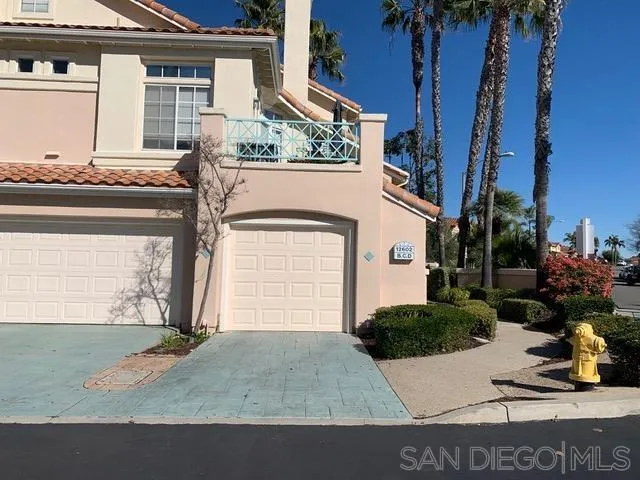 a view of a white house with potted plants