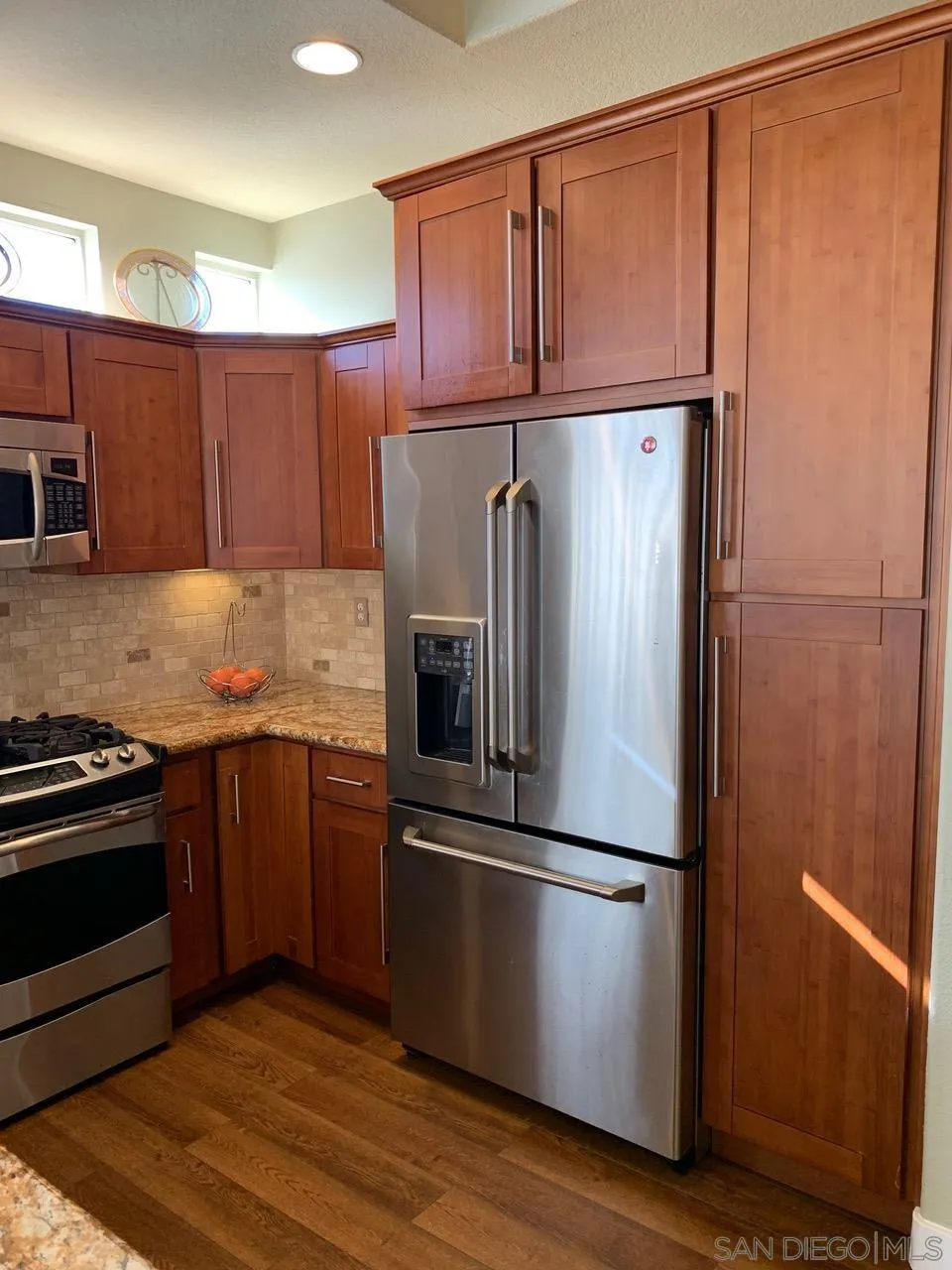 12602 Springbrook Drive, Unit B San Diego, CA 92128 - Photo 7 of 27 a kitchen with a refrigerator stainless steel appliances wooden floor and cabinets