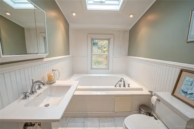 a bathroom with a bathtub a sink a toilet and a window