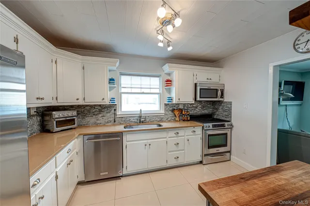 a kitchen with stainless steel appliances granite countertop a stove top oven a sink dishwasher and a refrigerator with wooden cabinets