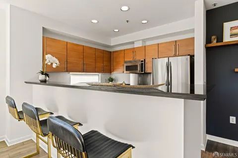 a kitchen with stainless steel appliances granite countertop a refrigerator a stove a sink a dining table and chairs with wooden floor