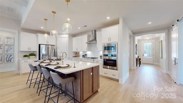 a kitchen with stainless steel appliances kitchen island granite countertop a stove a sink a refrigerator and a dining table with wooden floor