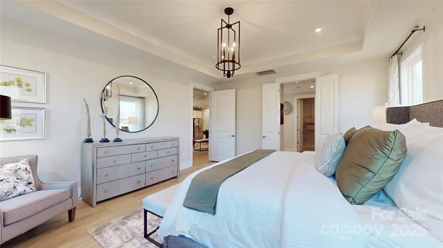 a bedroom with a bed a chandelier and mirror