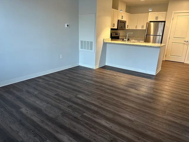 a kitchen with stainless steel appliances wooden floor and a sink
