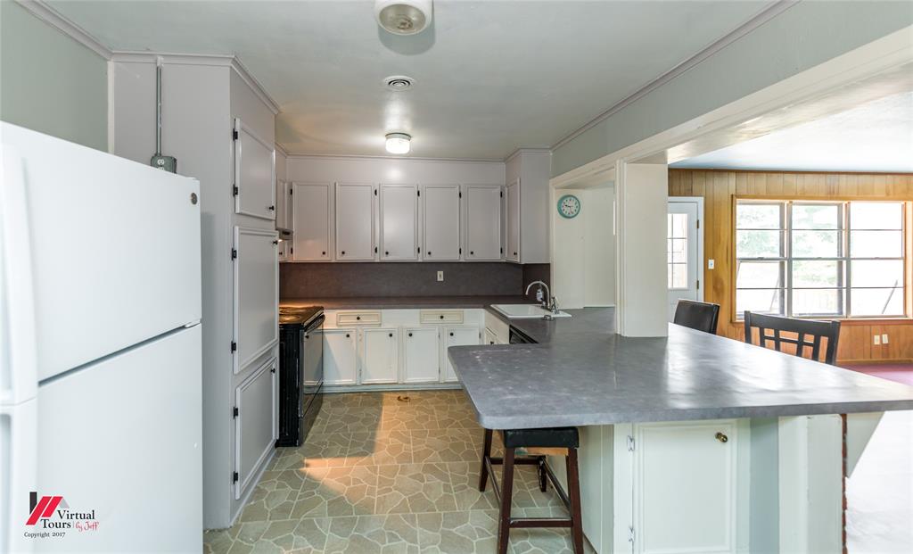 3109 Gorton Road Shreveport, LA 71119 - Photo 5 of 31 a kitchen with kitchen island a refrigerator a stove a dining table and chairs with wooden floor