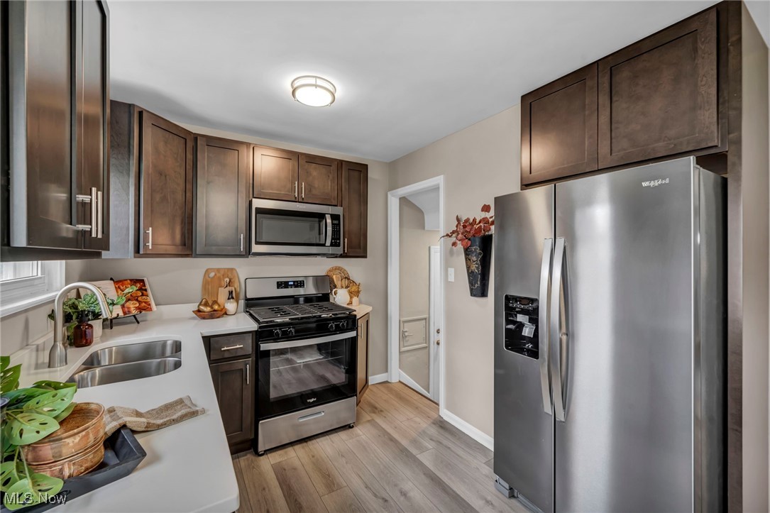 1560 Douglas Road Wickliffe, OH 44092 - Photo 14 of 39 Kitchen with stainless steel appliances, dark brown cabinets, light wood finished floors, and light stone counters
