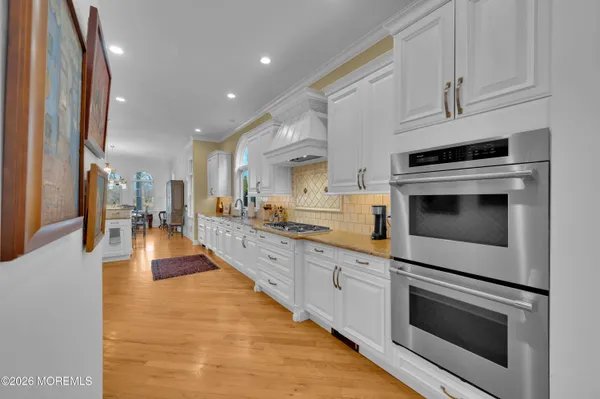 a large kitchen with kitchen island stainless steel appliances a table chairs sink and wooden floor