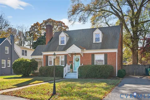 a view of a yard in front of a brick house with large windows