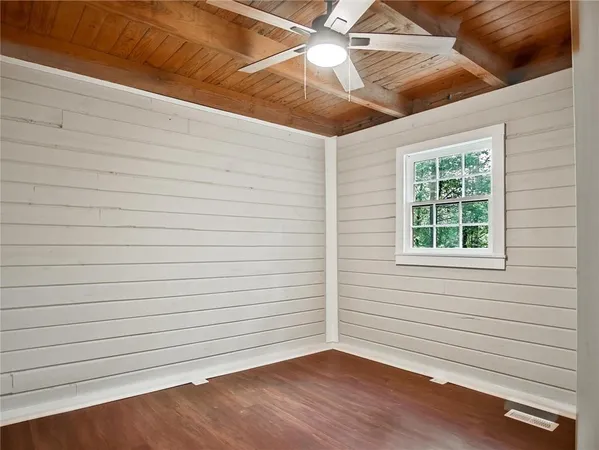 a view of an empty room with wooden floor and a ceiling fan