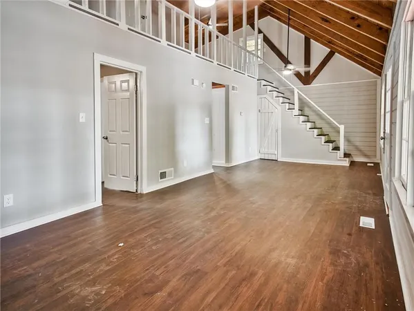 a view of an empty room with wooden floor and fan