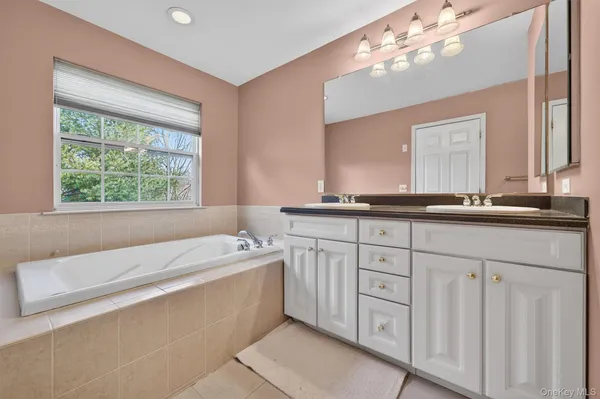 a bathroom with a sink a large mirror and a bathtub with a window