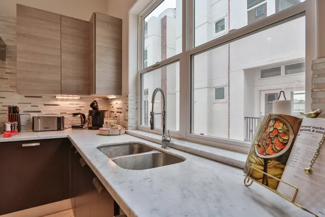 a kitchen with stainless steel appliances granite countertop a sink and a stove next to a window