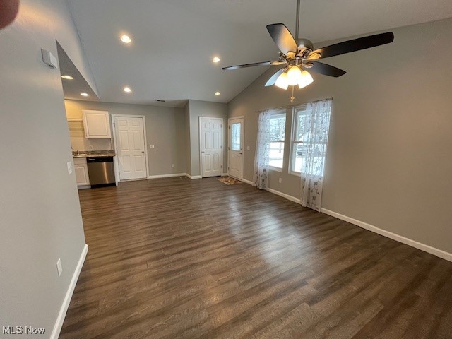 Unfurnished living room with dark hardwood / wood-style floors, vaulted ceiling, and ceiling fan