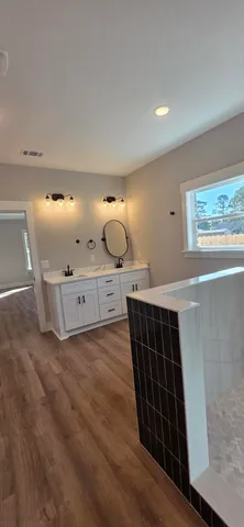 an empty room with wooden floor ceiling fan and windows