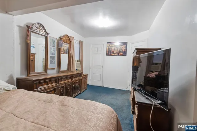 a bedroom with a bed and a flat tv screen on the dresser