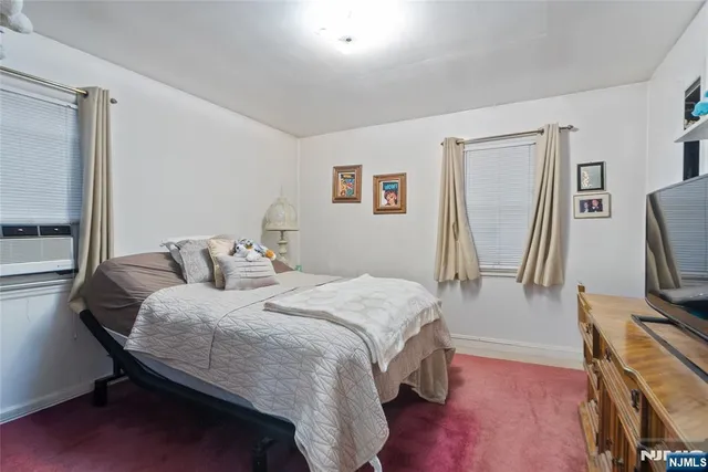 a bedroom with a bed table flat screen tv and a window