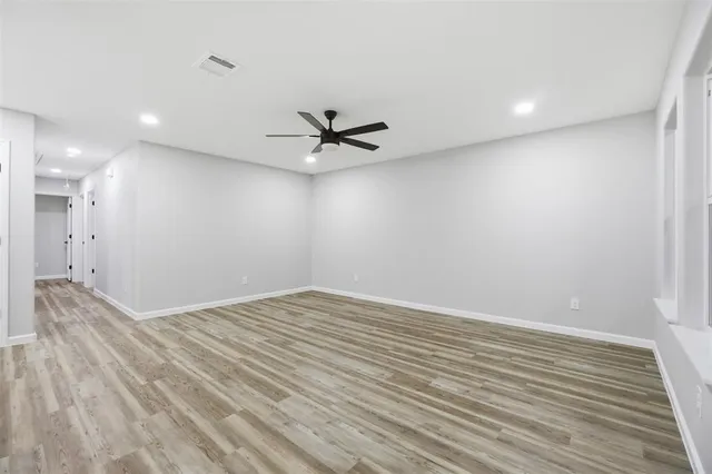 an empty room with wooden floor and a ceiling fan