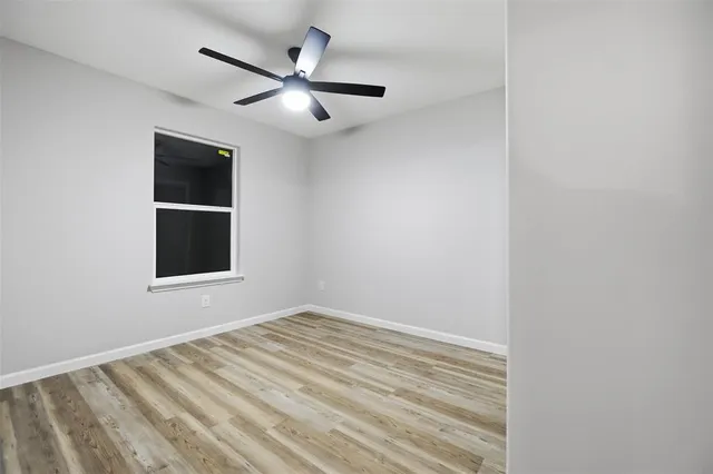 an empty room with a window and ceiling fan