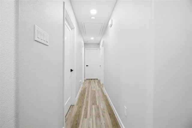 a view of a hallway with wooden floor and a chandelier