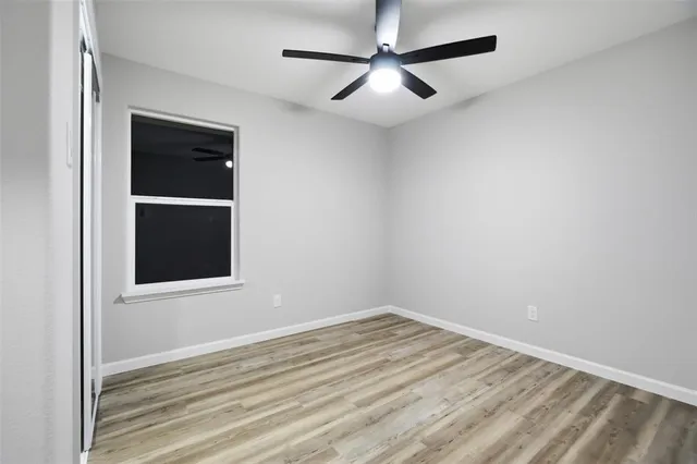 an empty room with a window and ceiling fan
