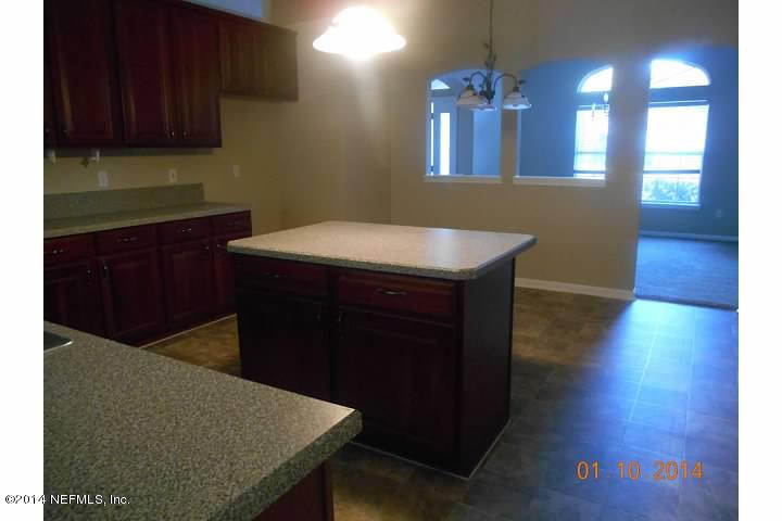 97226 Castle Ridge Drive Yulee, FL 32097 - Photo 7 of 15 a kitchen with a wooden floor and cabinets