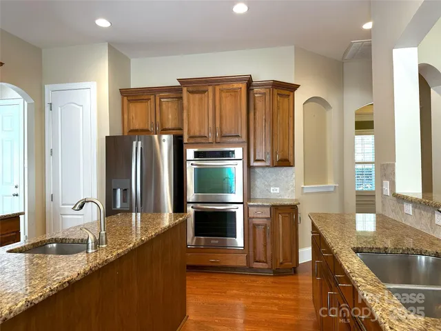 a kitchen with stainless steel appliances granite countertop a sink a stove and a refrigerator
