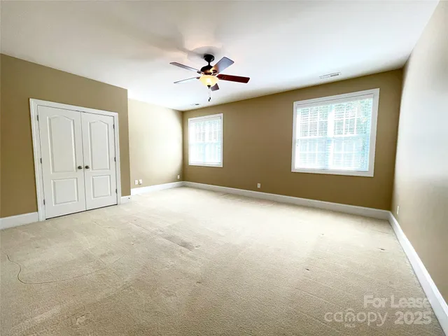 an empty room with windows and ceiling fan
