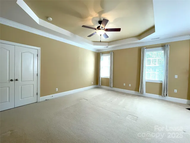 an empty room with chandelier fan and windows