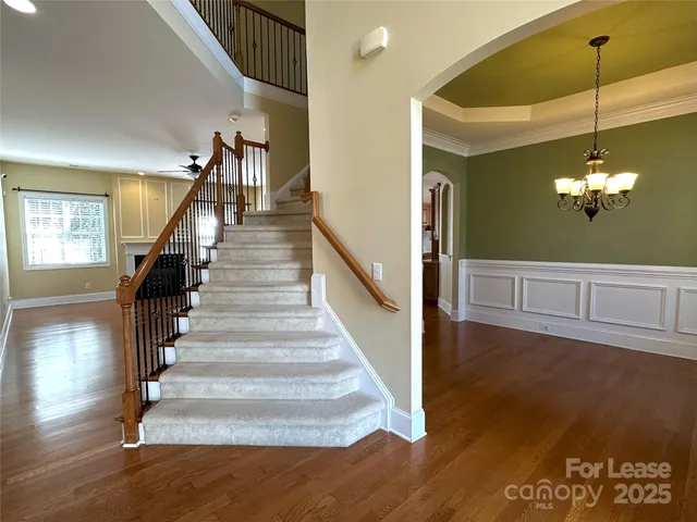 a view of a hallway with stairs and wooden floor