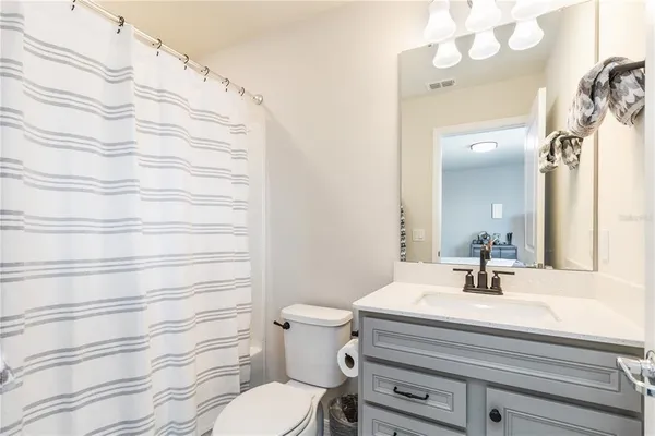 a bathroom with a sink a toilet a mirror a vanity and bathtub
