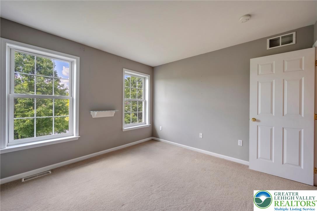 204 Bushkill Ridge Road Wind Gap, PA 18091 - Photo 35 of 48 A quiet bedroom offers serene views of lush, mature trees through well-lit windows.
