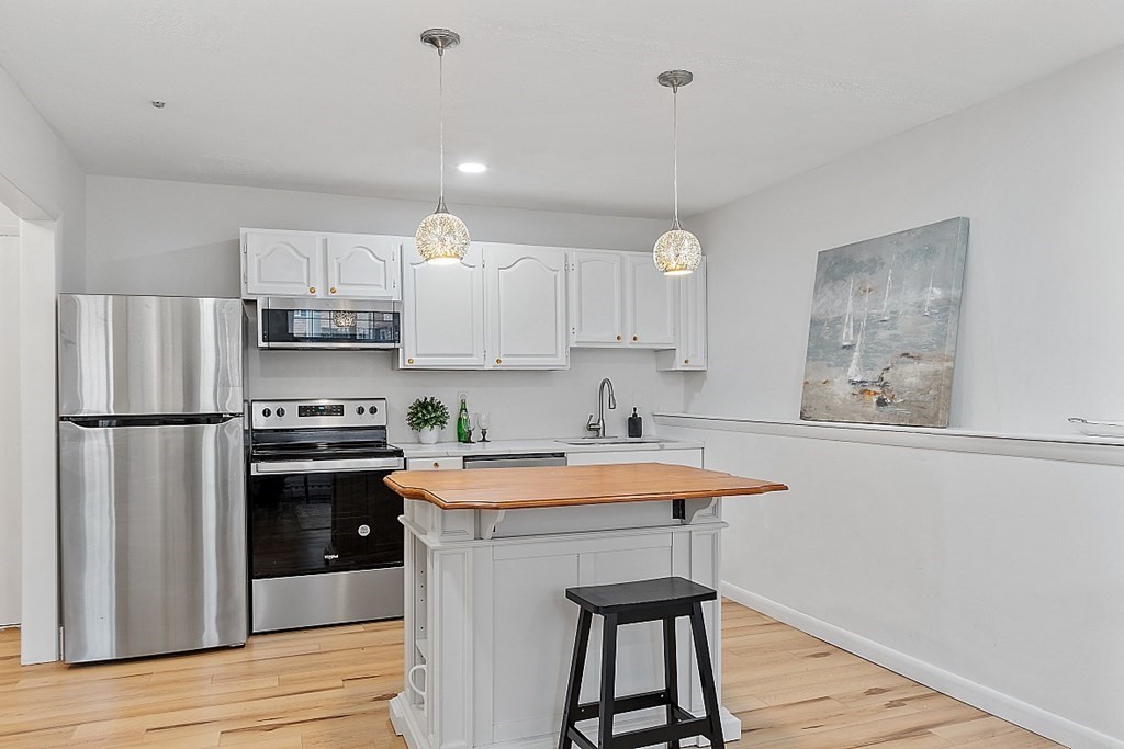 6 Leonard Road, Unit 6 Boxborough, MA 01719 - Photo 6 of 28 a kitchen with stainless steel appliances a sink a stove a refrigerator cabinets and wooden floor